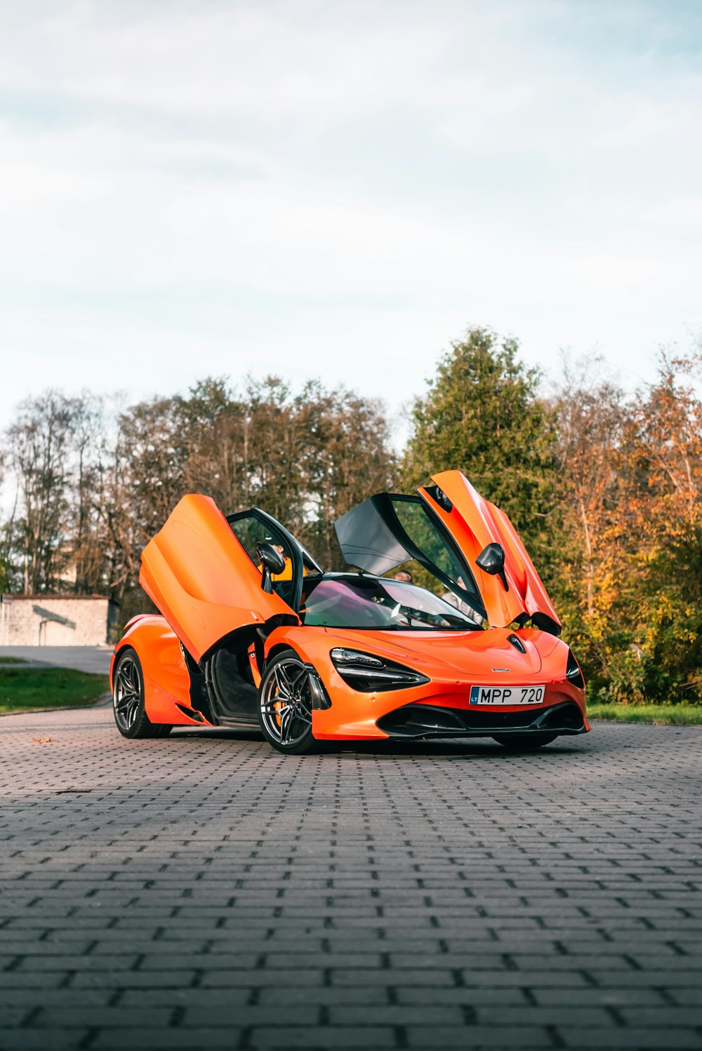 an orange sports car parked on a brick road