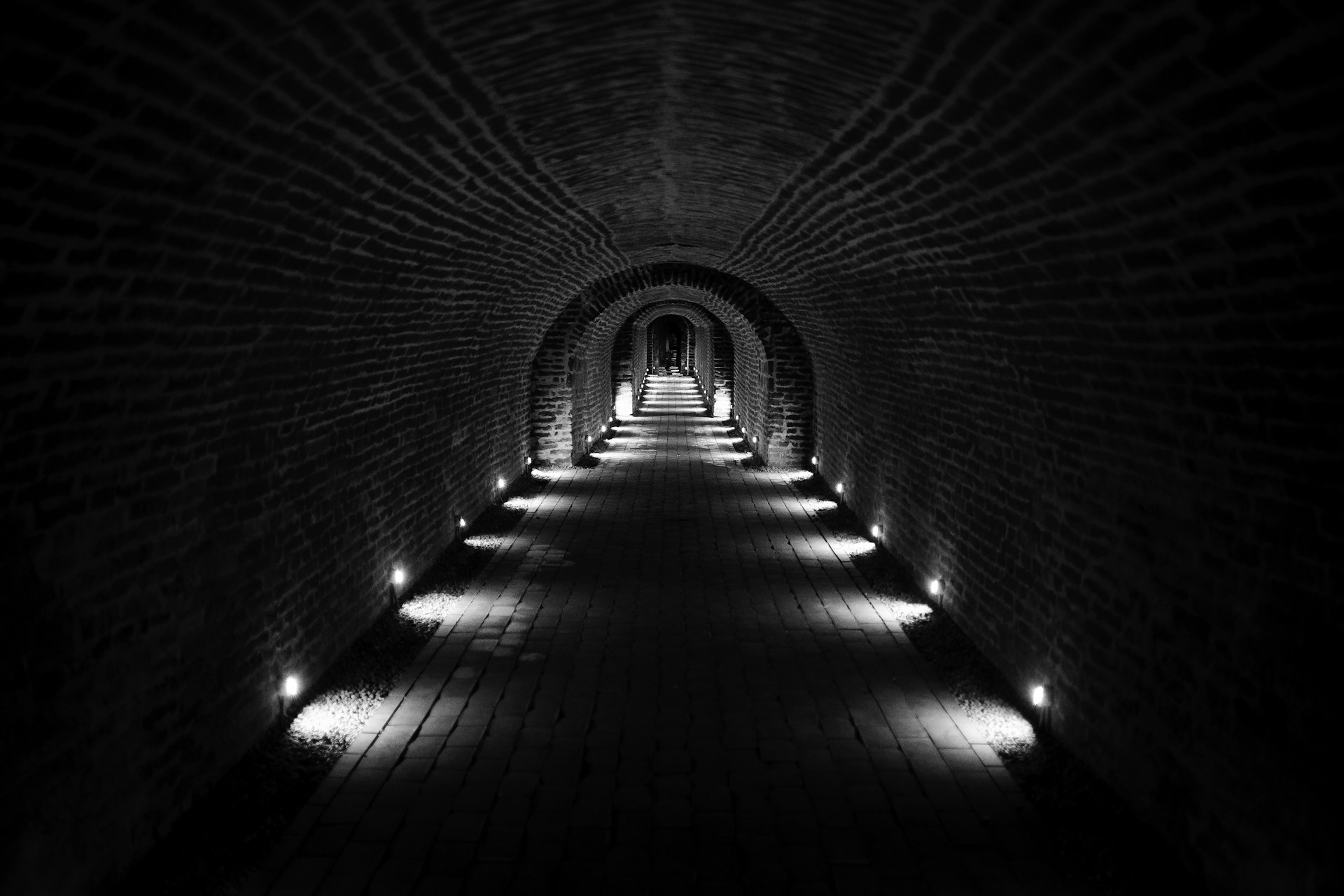a long brick tunnel with lights at the end
