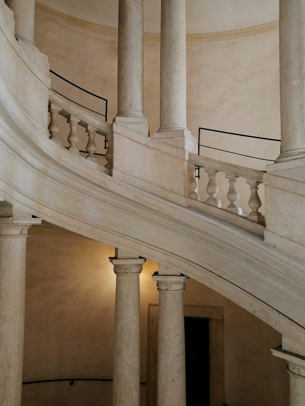 a spiral staircase in a building with marble columns