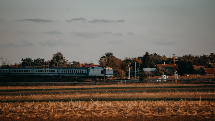 a train traveling through a rural countryside under a cloudy sky