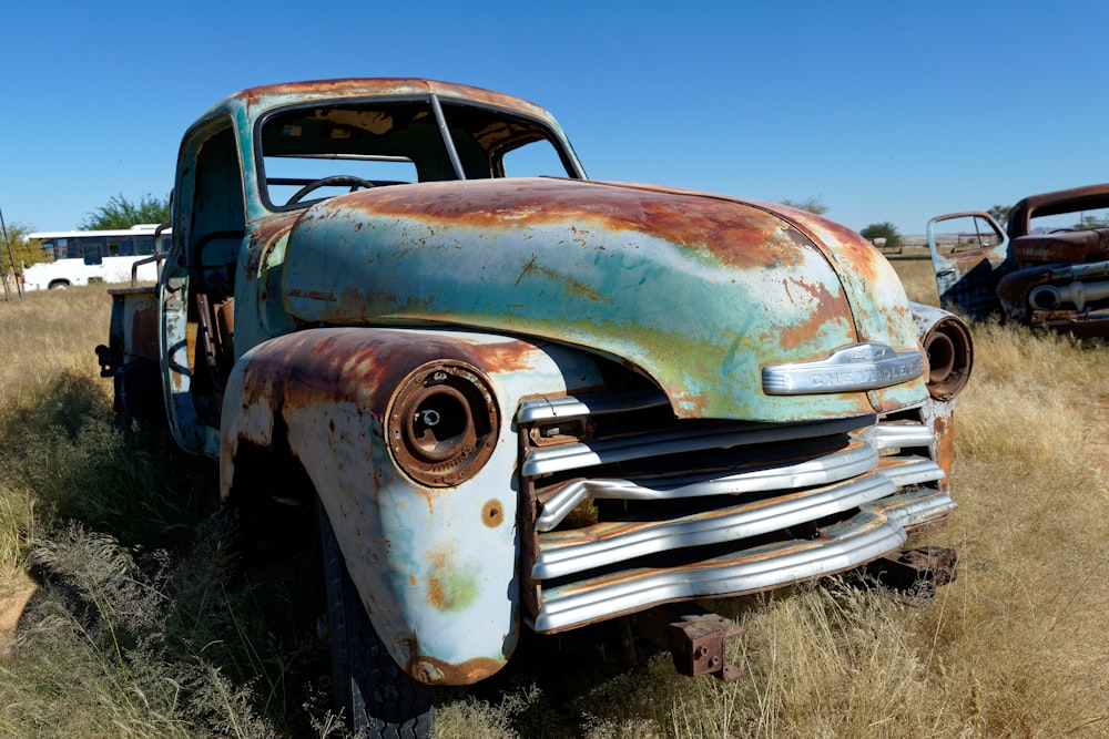 an old rusty truck sitting in a field