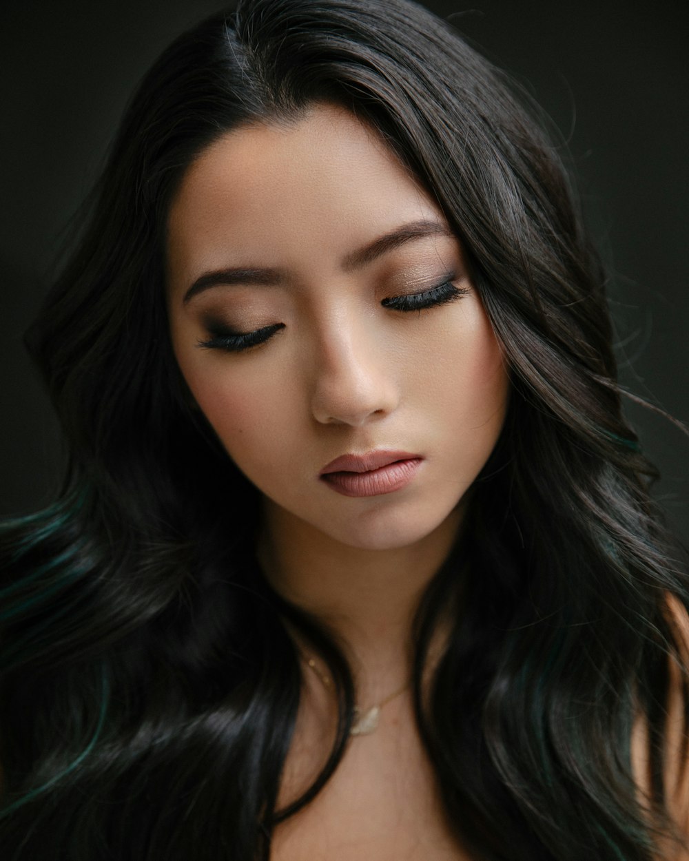 a woman with long black hair wearing a necklace