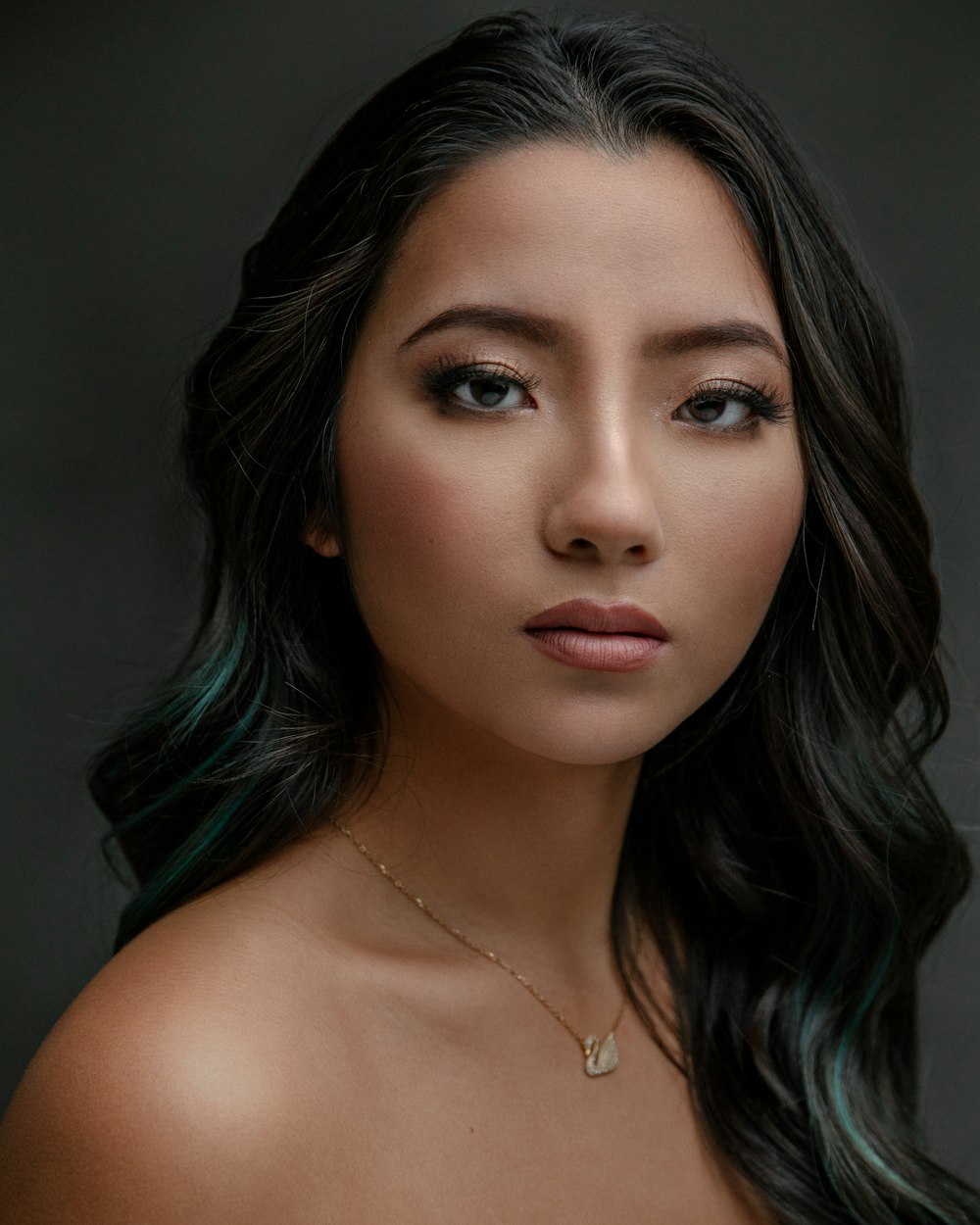 a woman with long black hair wearing a necklace