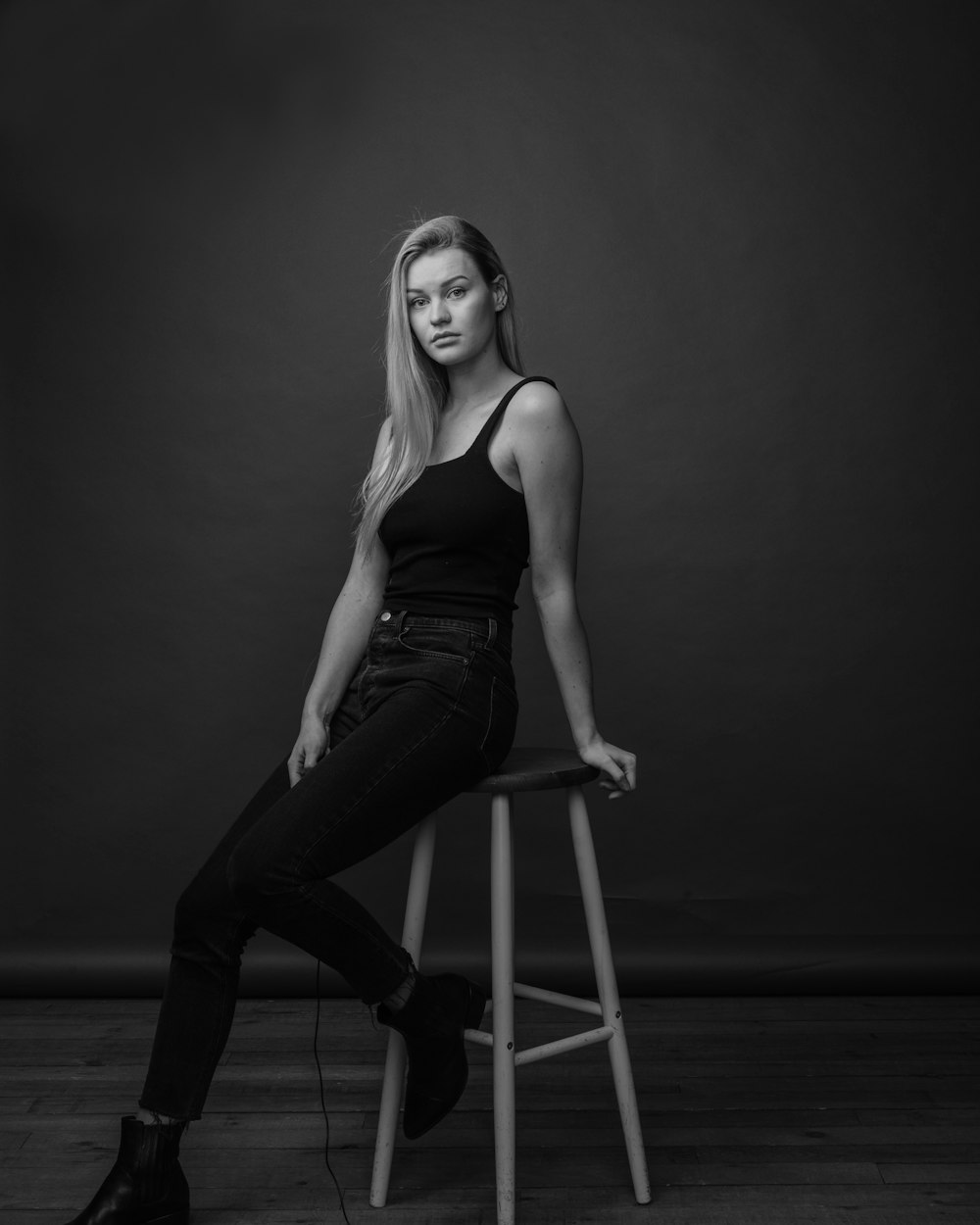 a woman sitting on a stool in a black and white photo