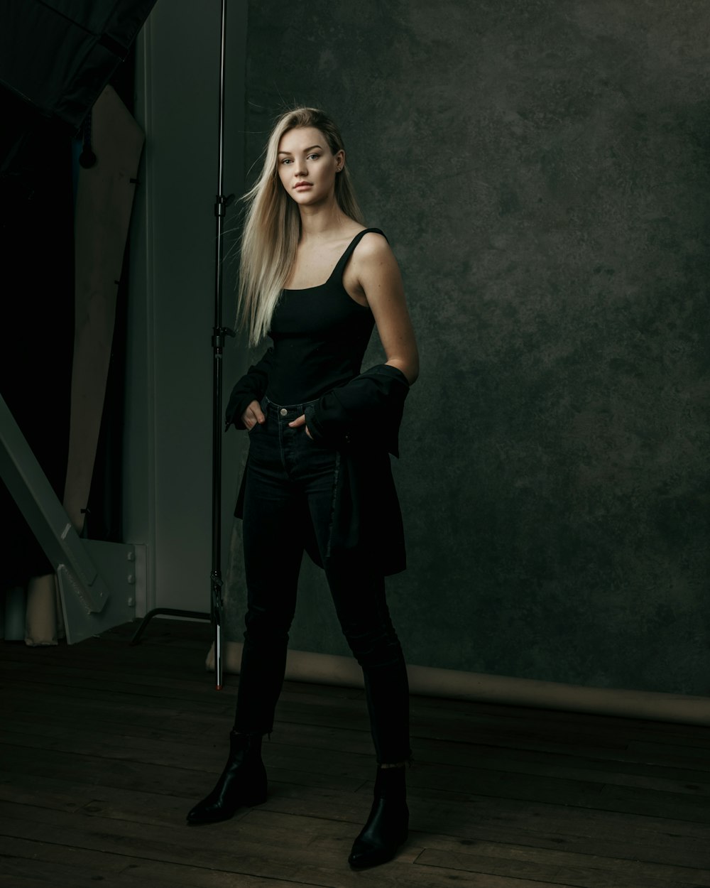 a woman standing in a dark room with her hands on her hips