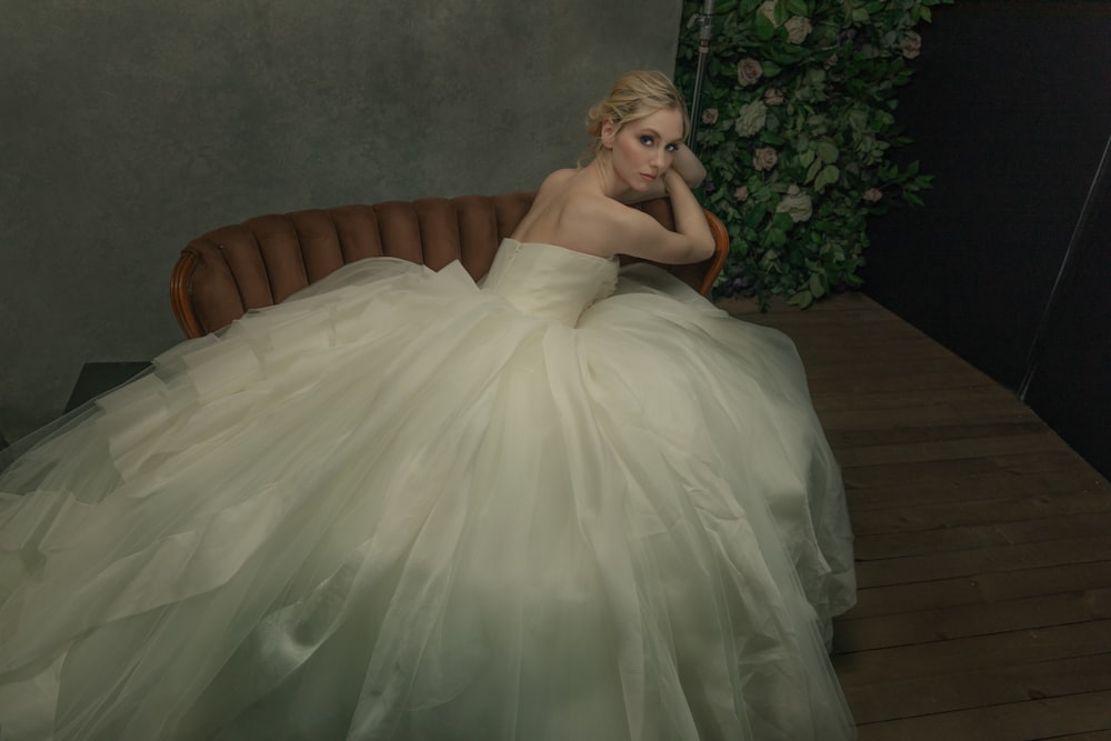 a woman in a white dress sitting on a couch