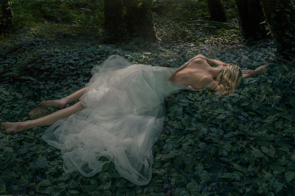 a woman laying on the ground in a forest