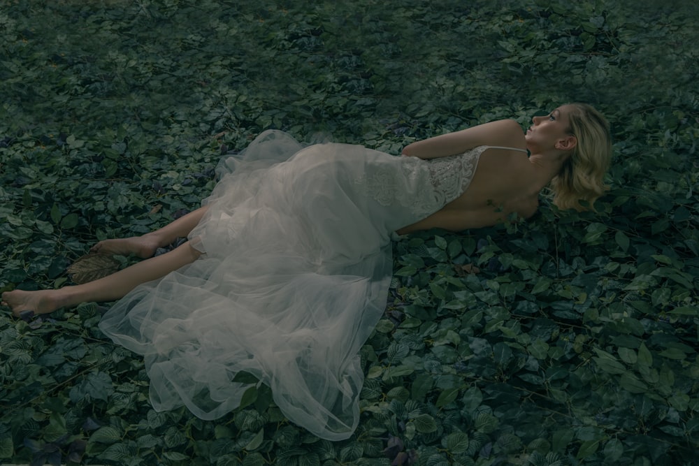 a woman laying on the ground in a white dress
