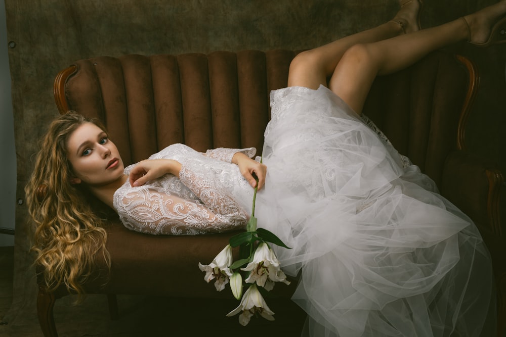 a woman in a white dress laying on a couch