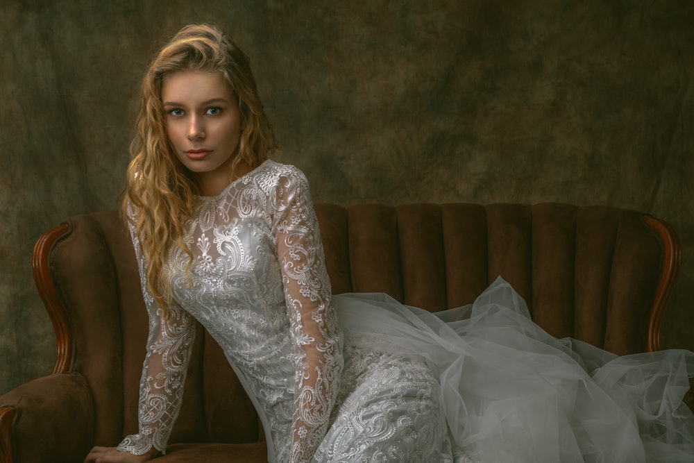 a woman in a white dress sitting on a couch