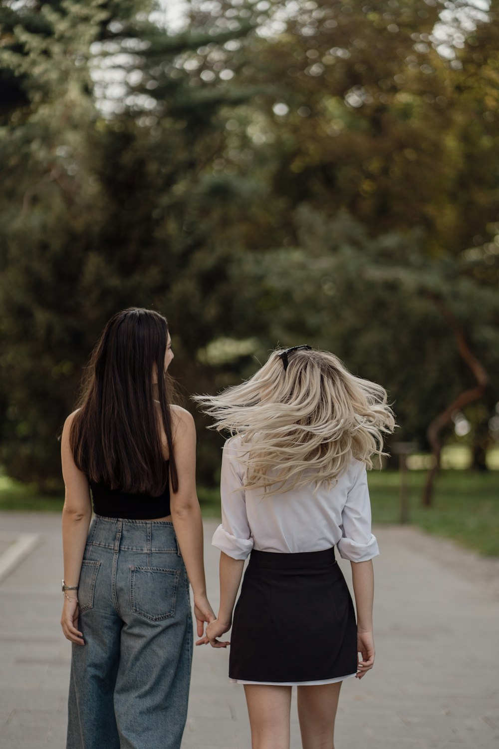 two women walking down a sidewalk holding hands