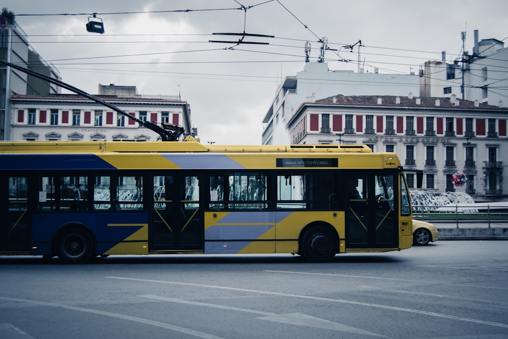 a yellow and blue bus driving down a street
