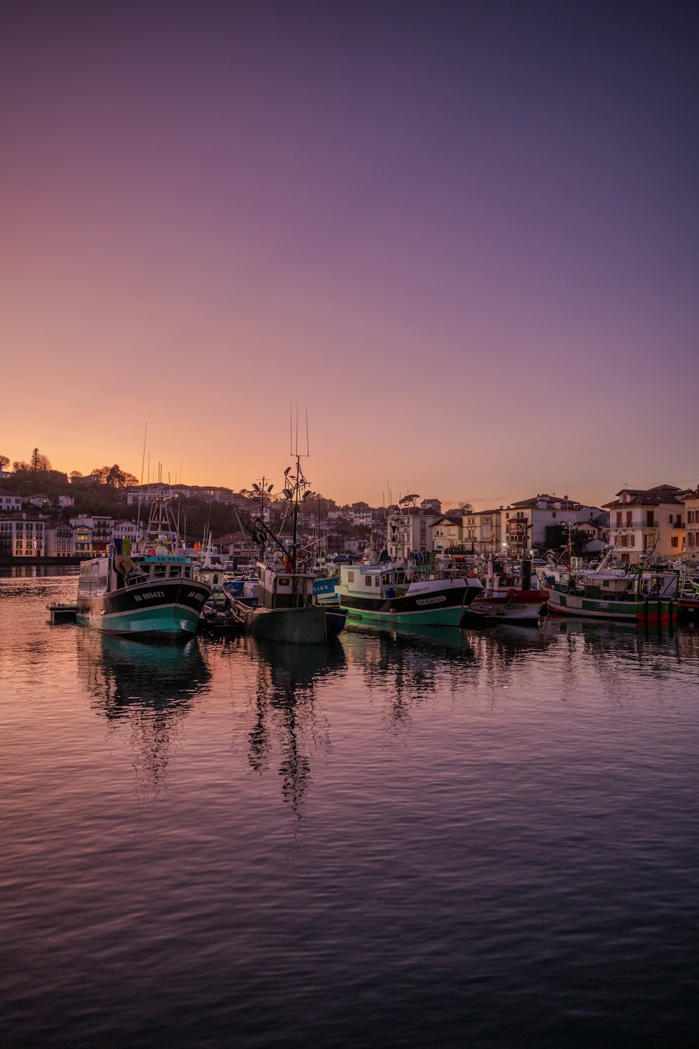 a harbor filled with lots of boats under a purple sky