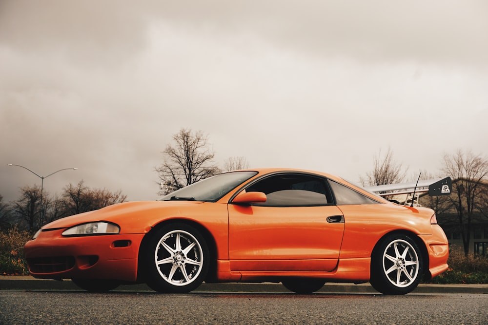 an orange sports car parked on the side of the road