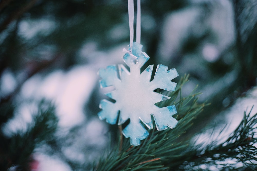 a snowflake ornament hanging from a pine tree