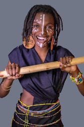 a woman holding a wooden stick with a painted face