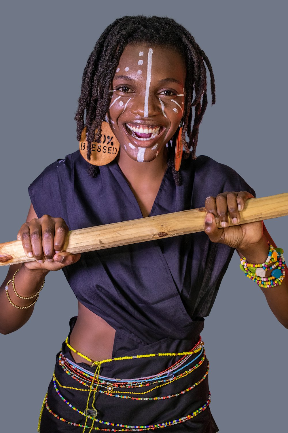 a woman holding a wooden stick with a painted face