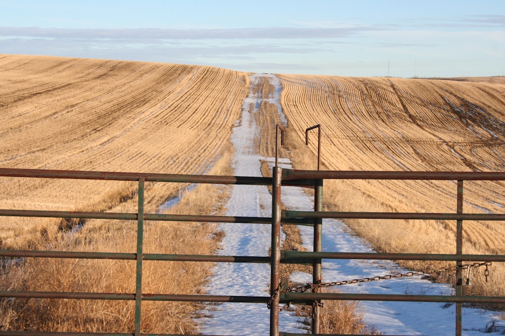 a road that is next to a field with snow on the ground