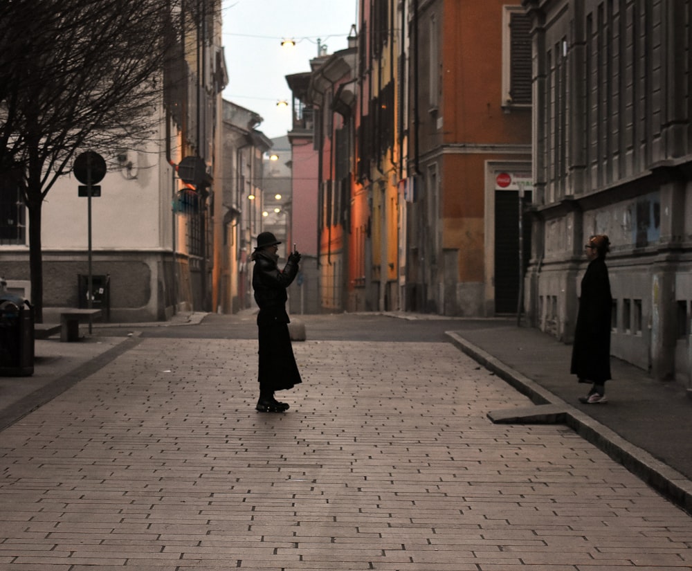 eine Frau, die auf einer Backsteinstraße steht und einen Regenschirm in der Hand hält