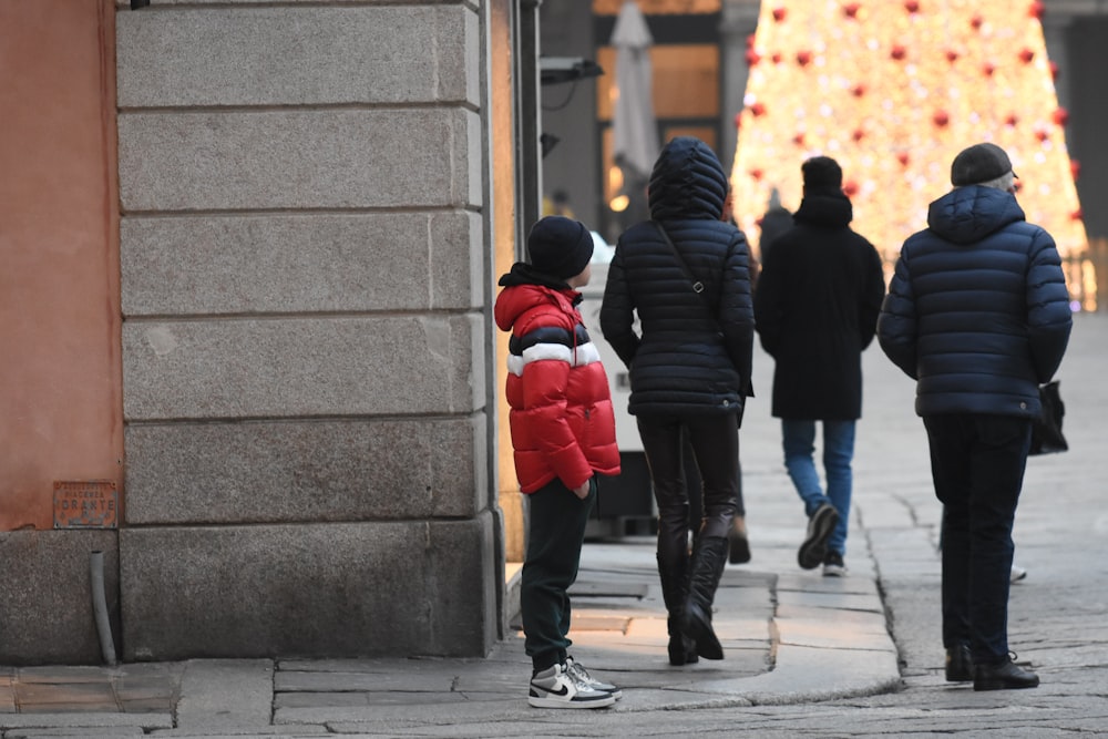 a group of people walking down a street next to a christmas tree