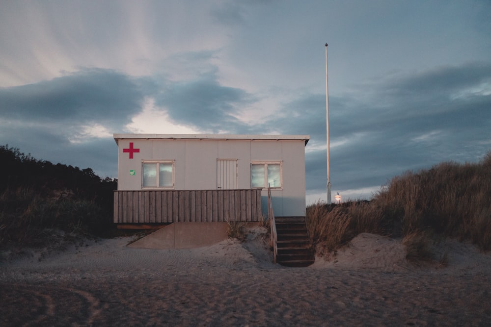a house on a beach with a red cross on it