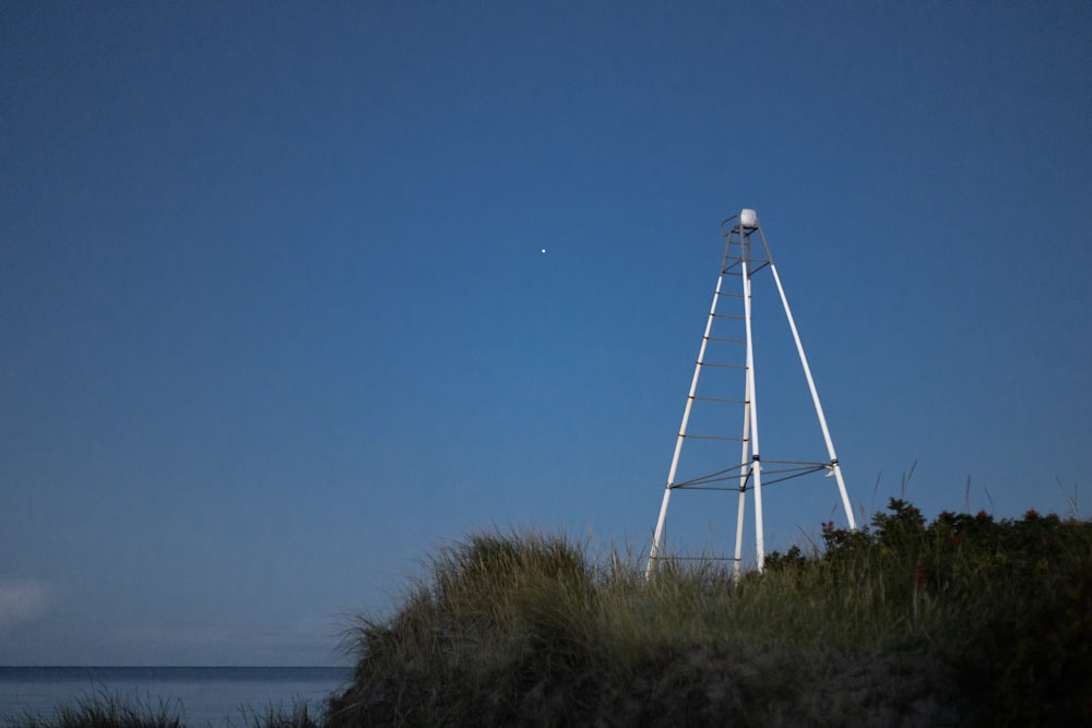 a tall white windmill sitting on top of a lush green field