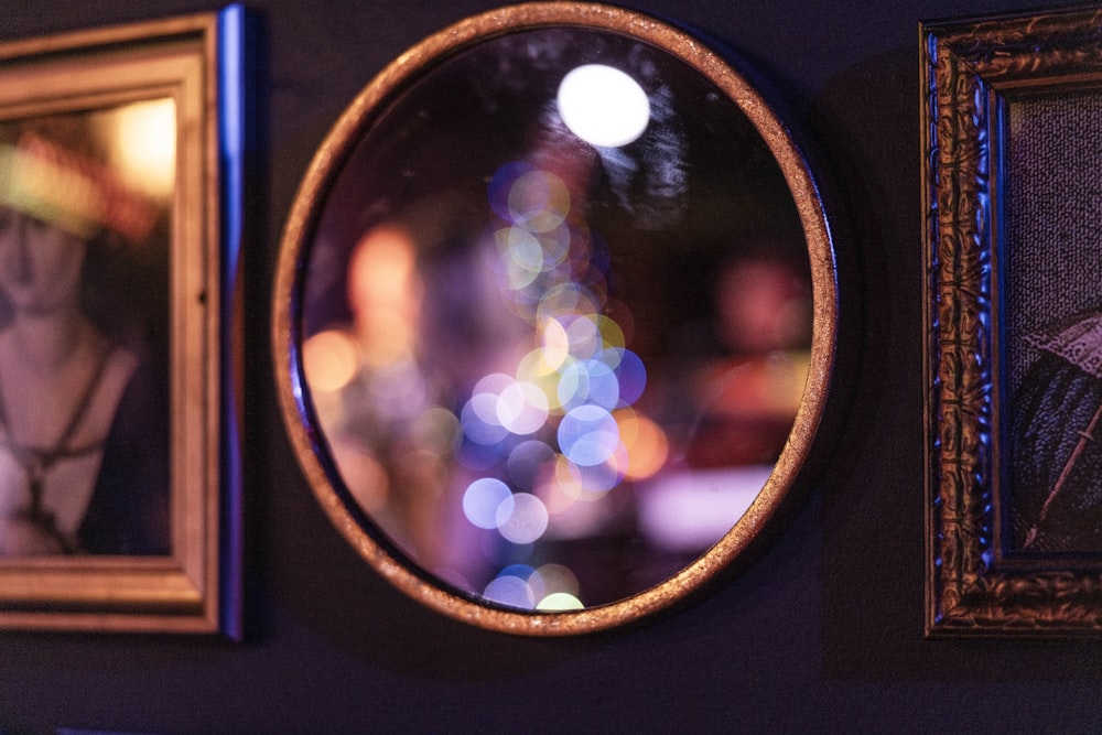 a wall with three framed pictures and a round mirror