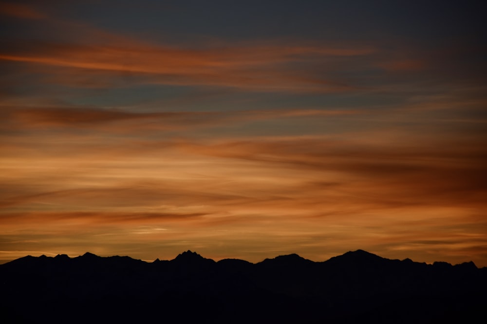 a plane flying in the sky with a sunset in the background