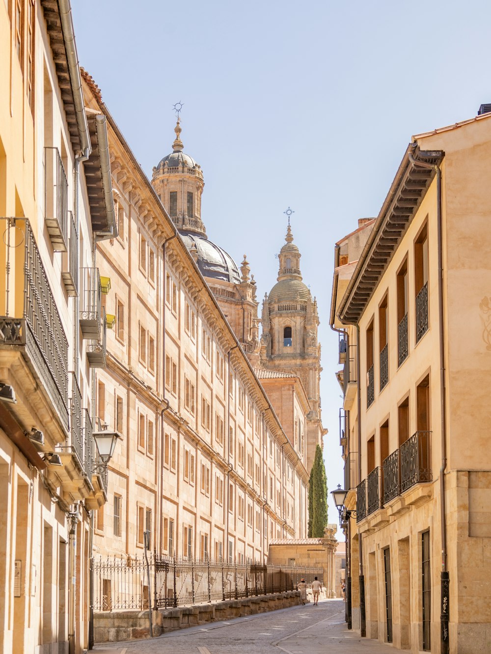 Una calle de la ciudad con edificios y una torre del reloj al fondo