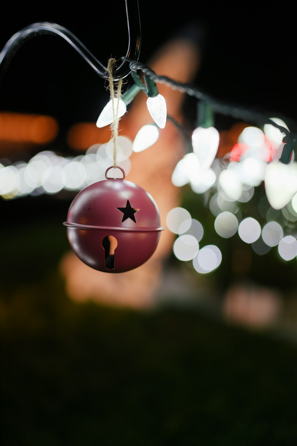 a christmas ornament hanging from a tree with lights in the background