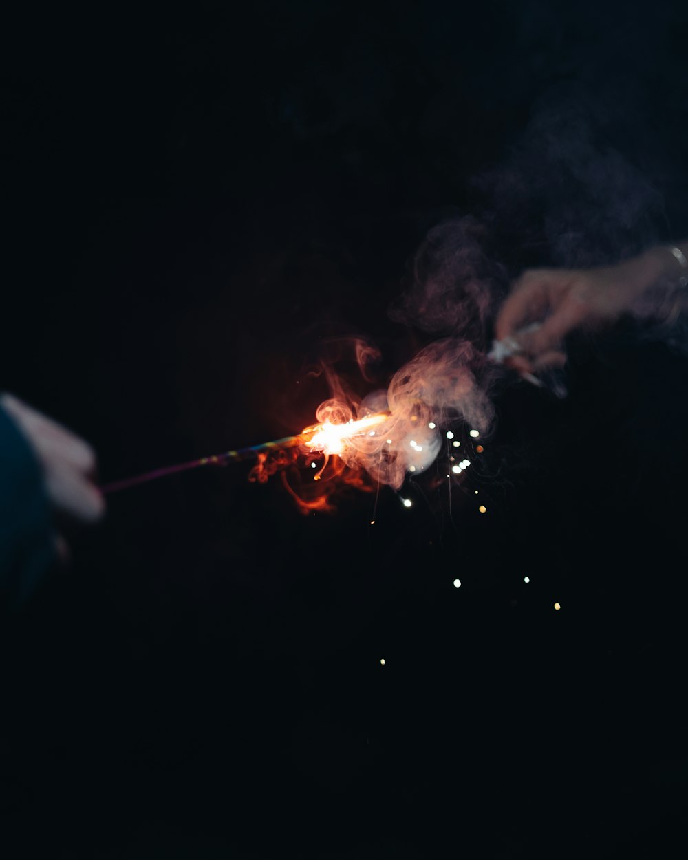 a person holding a lit sparkler in the dark