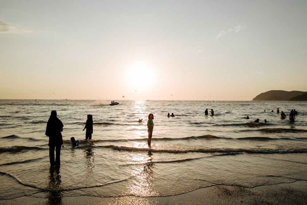 a group of people standing on top of a beach next to the ocean