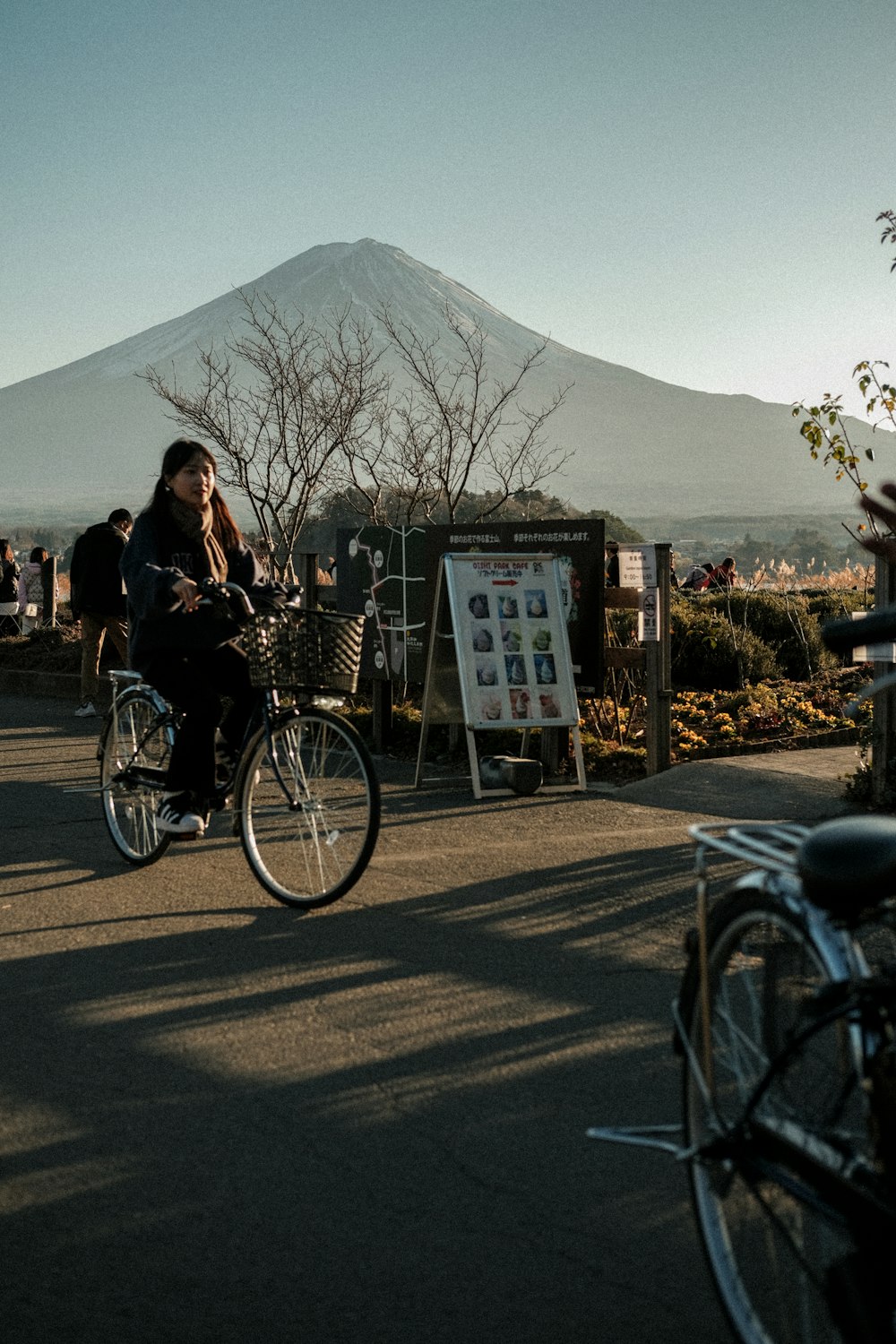 a woman riding a bike down a street next to a mountain