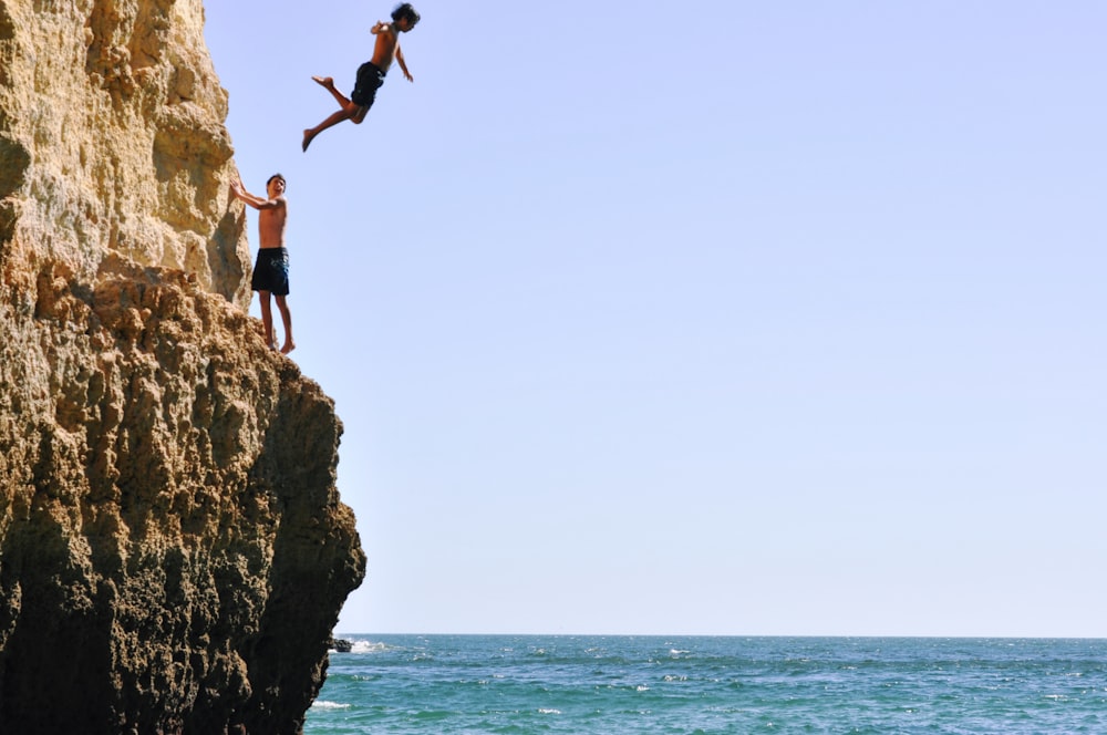 Zwei Menschen springen von einer Klippe ins Meer