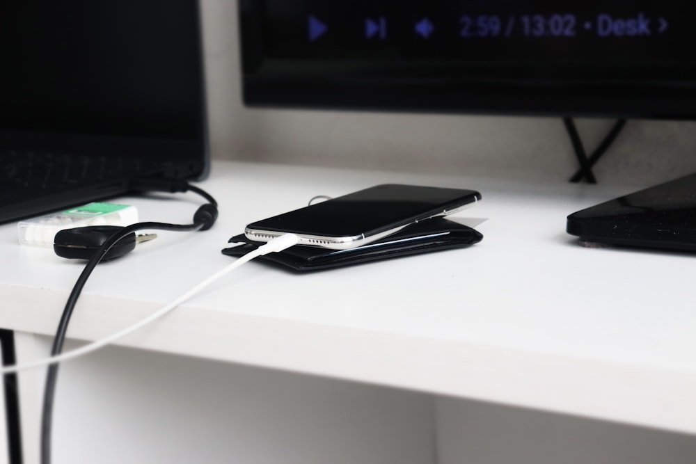 a white desk topped with a laptop computer and a cell phone