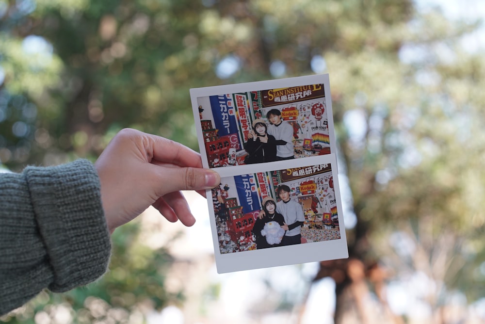 a person holding up a polaroid picture of themselves