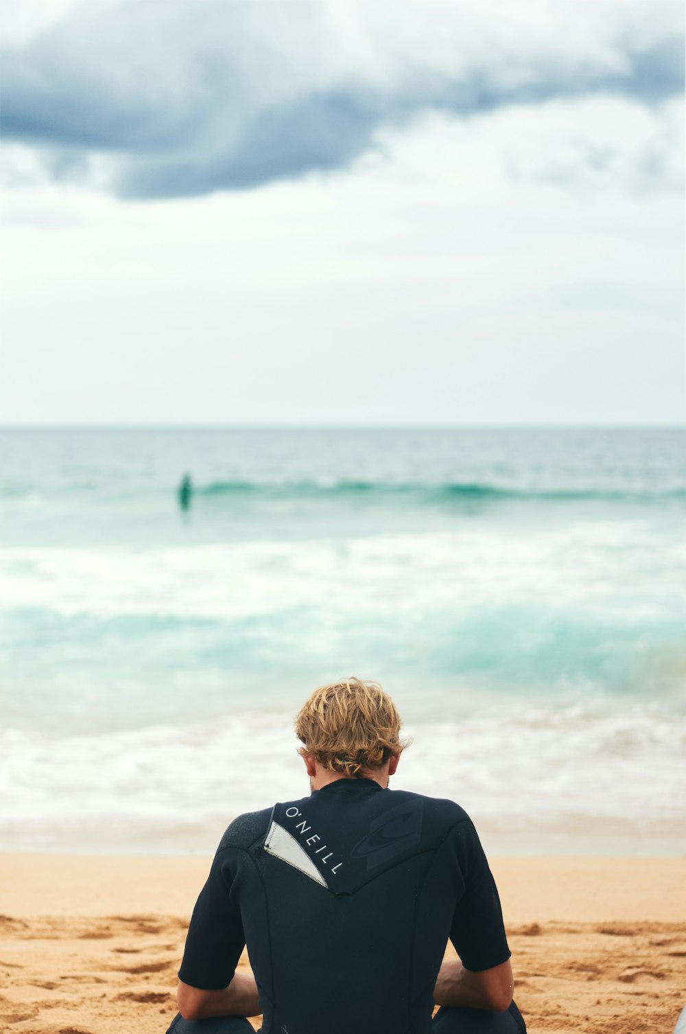 a man sitting on a beach with a surfboard