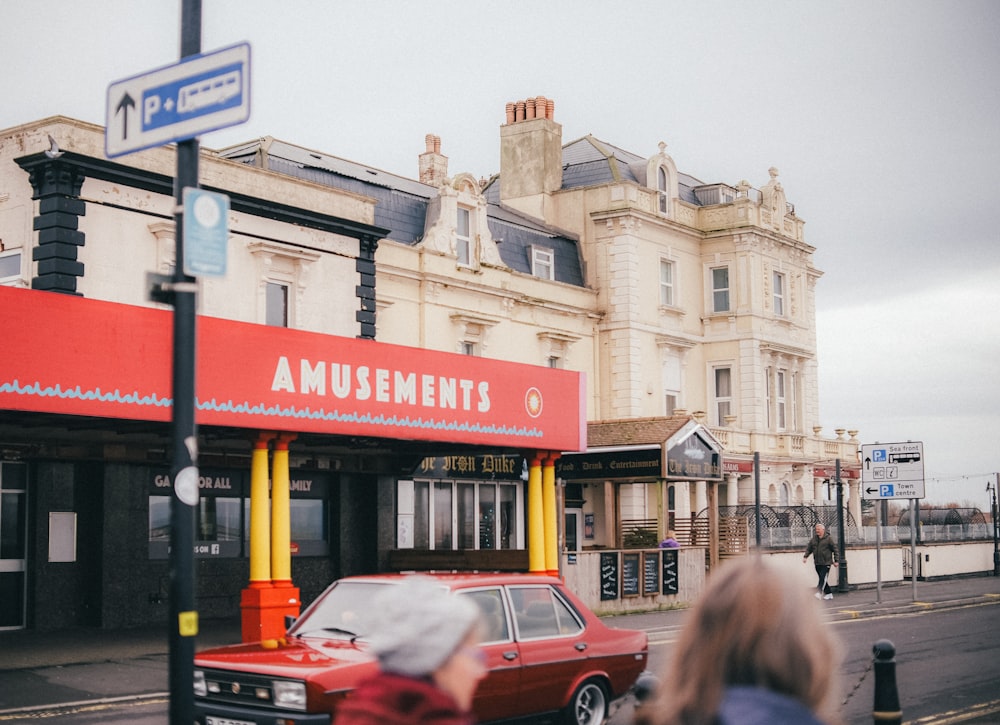 a red car driving past an amusement arcade