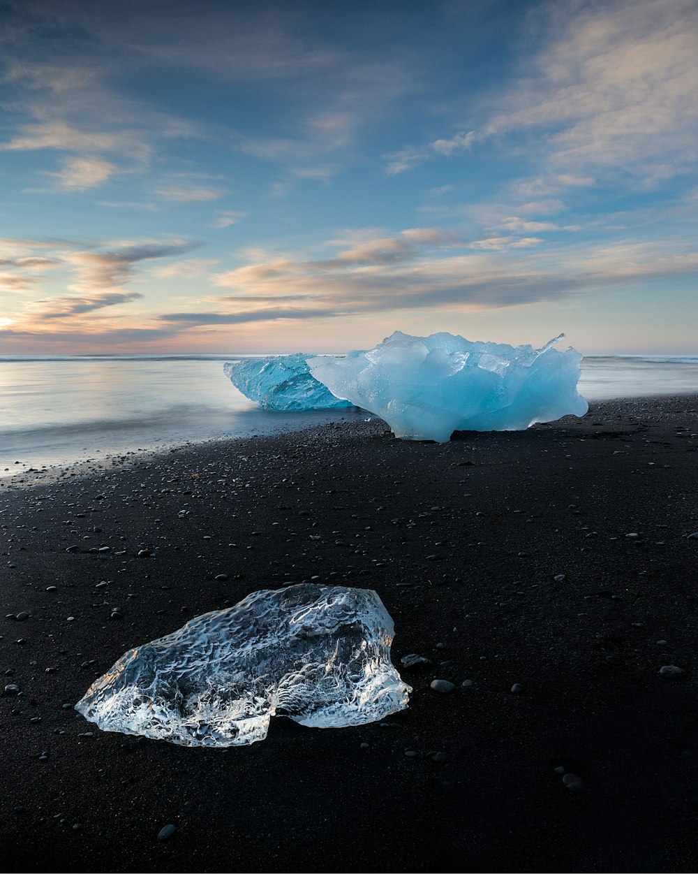 a large iceberg floating on top of a sandy beach