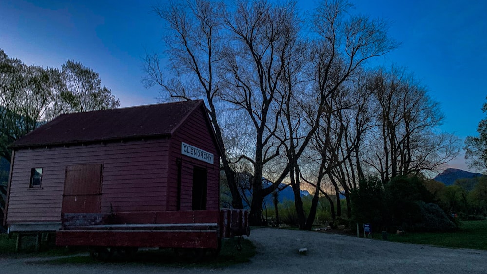 a small red building sitting in the middle of a forest