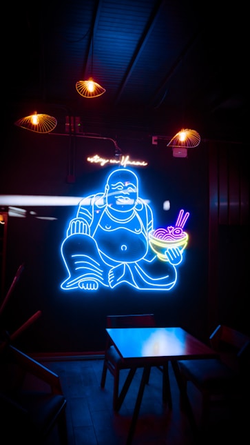 a neon sign of a buddha holding a bowl of food