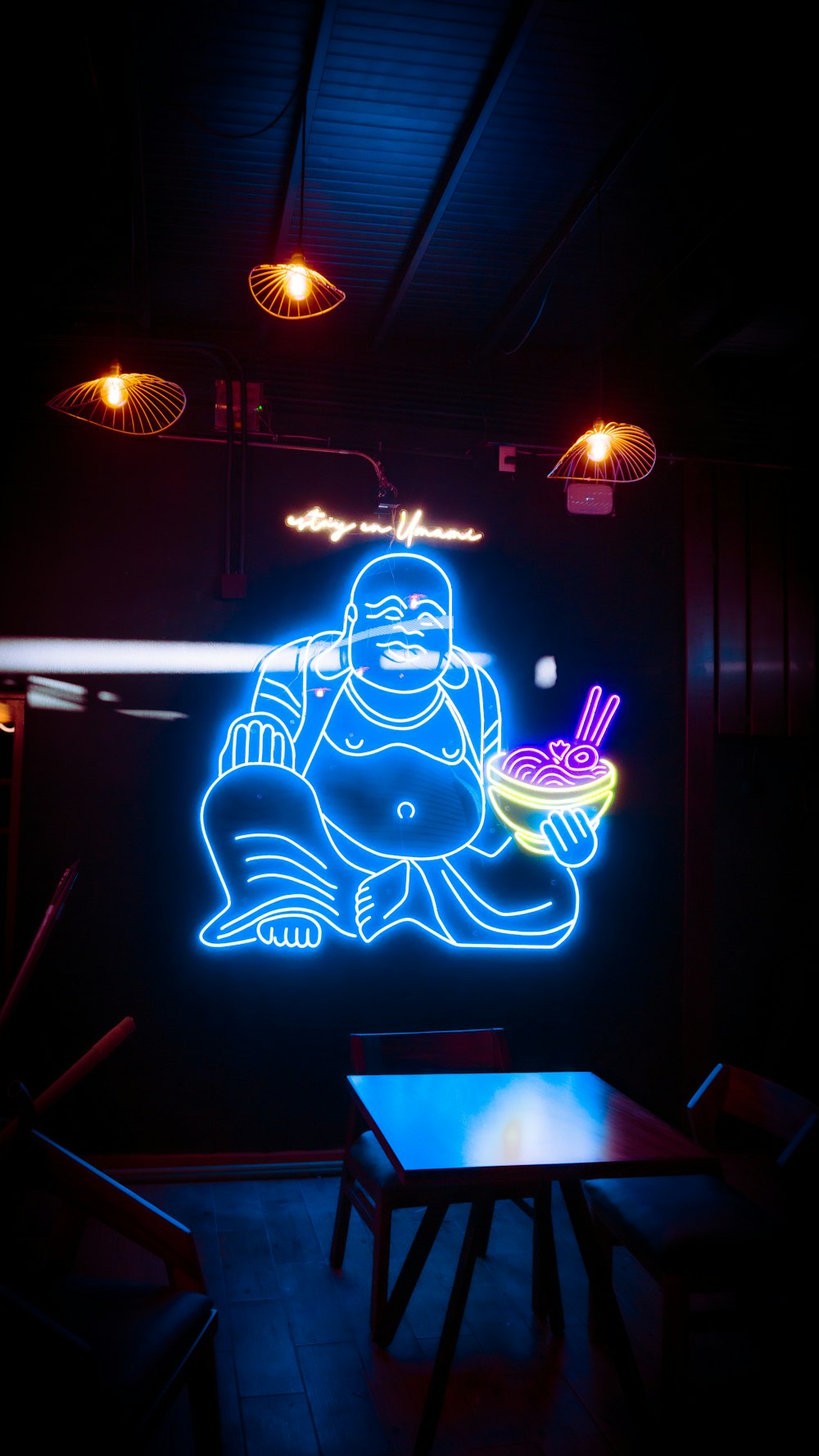 a neon sign of a buddha holding a bowl of food