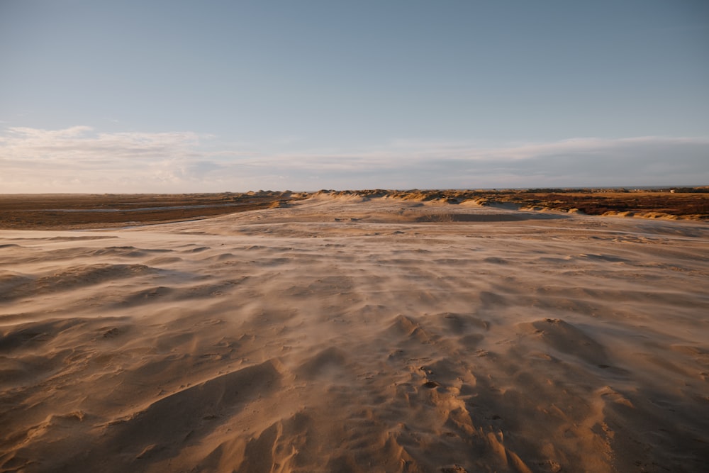 a sandy beach covered in sand under a blue sky