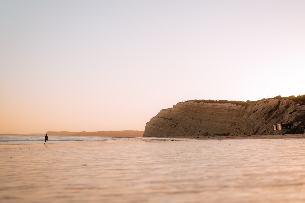 a person standing on a beach next to a cliff