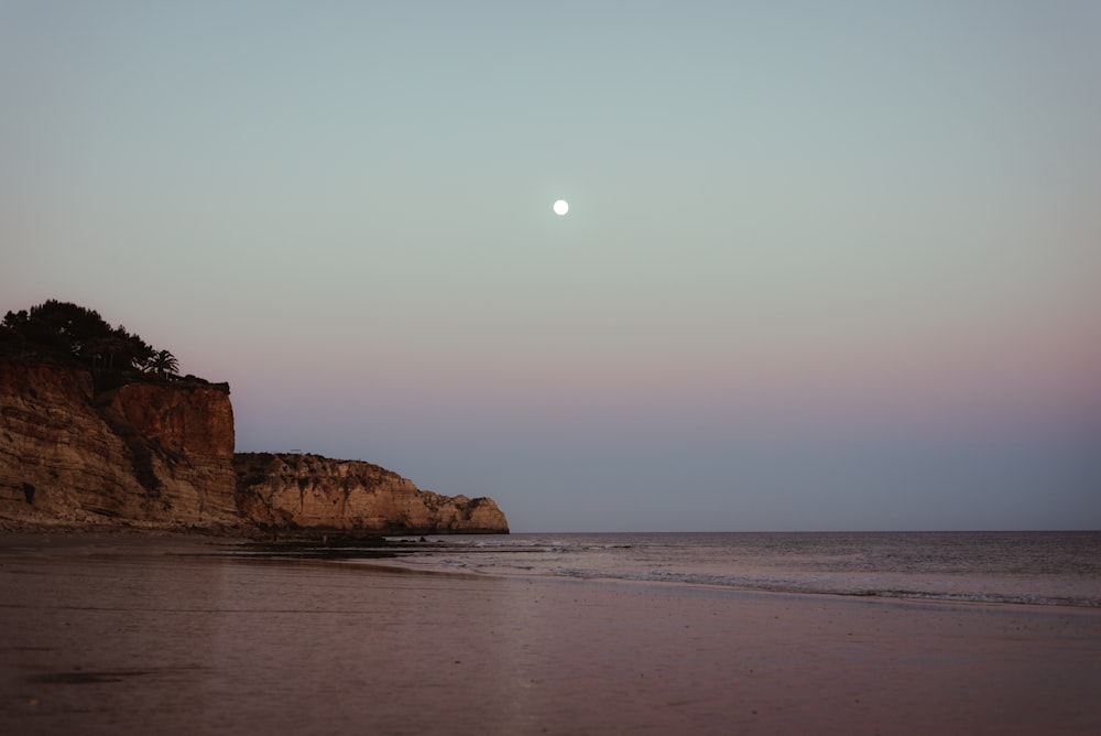 a full moon is seen over the ocean