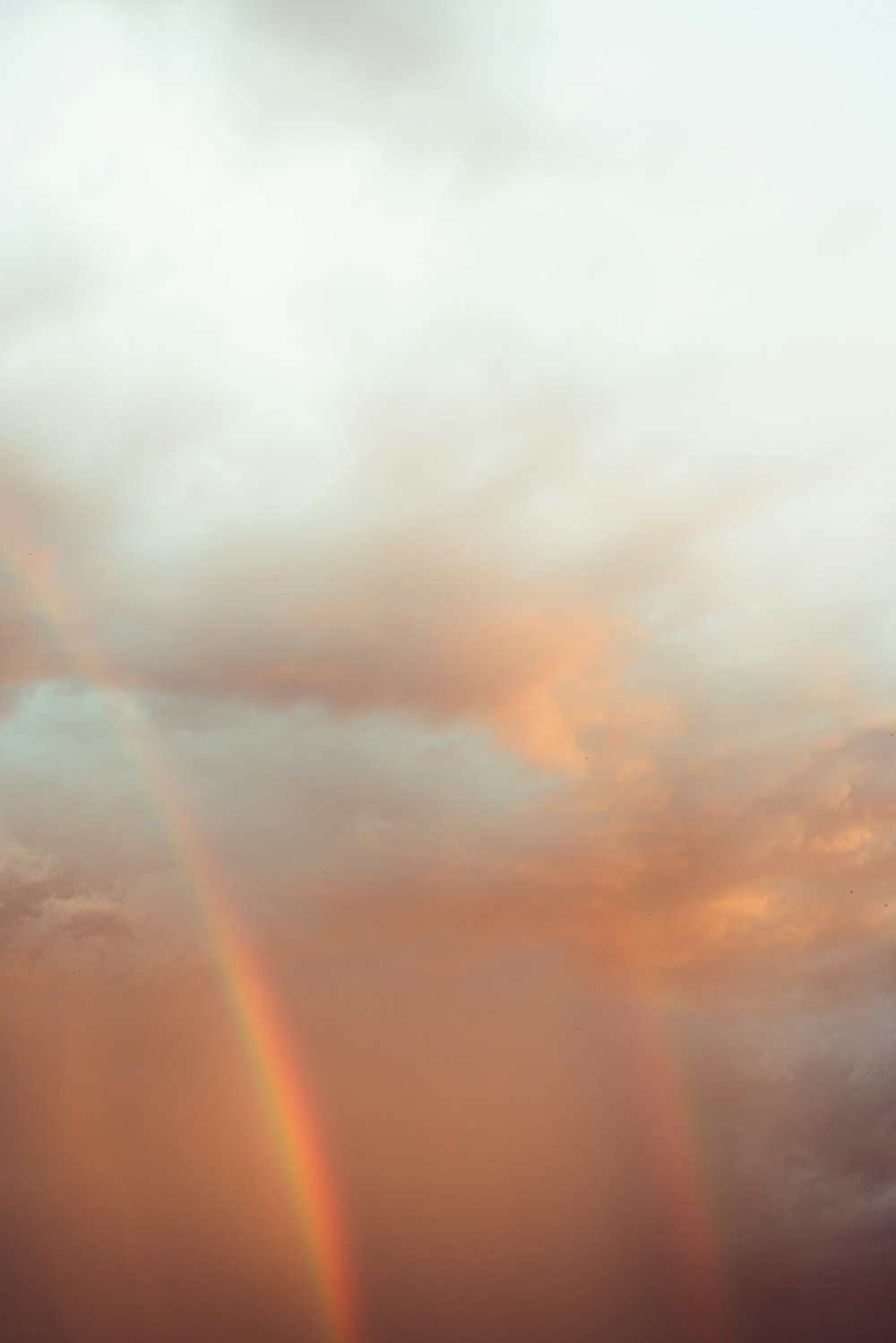 a rainbow appears in the sky over a beach