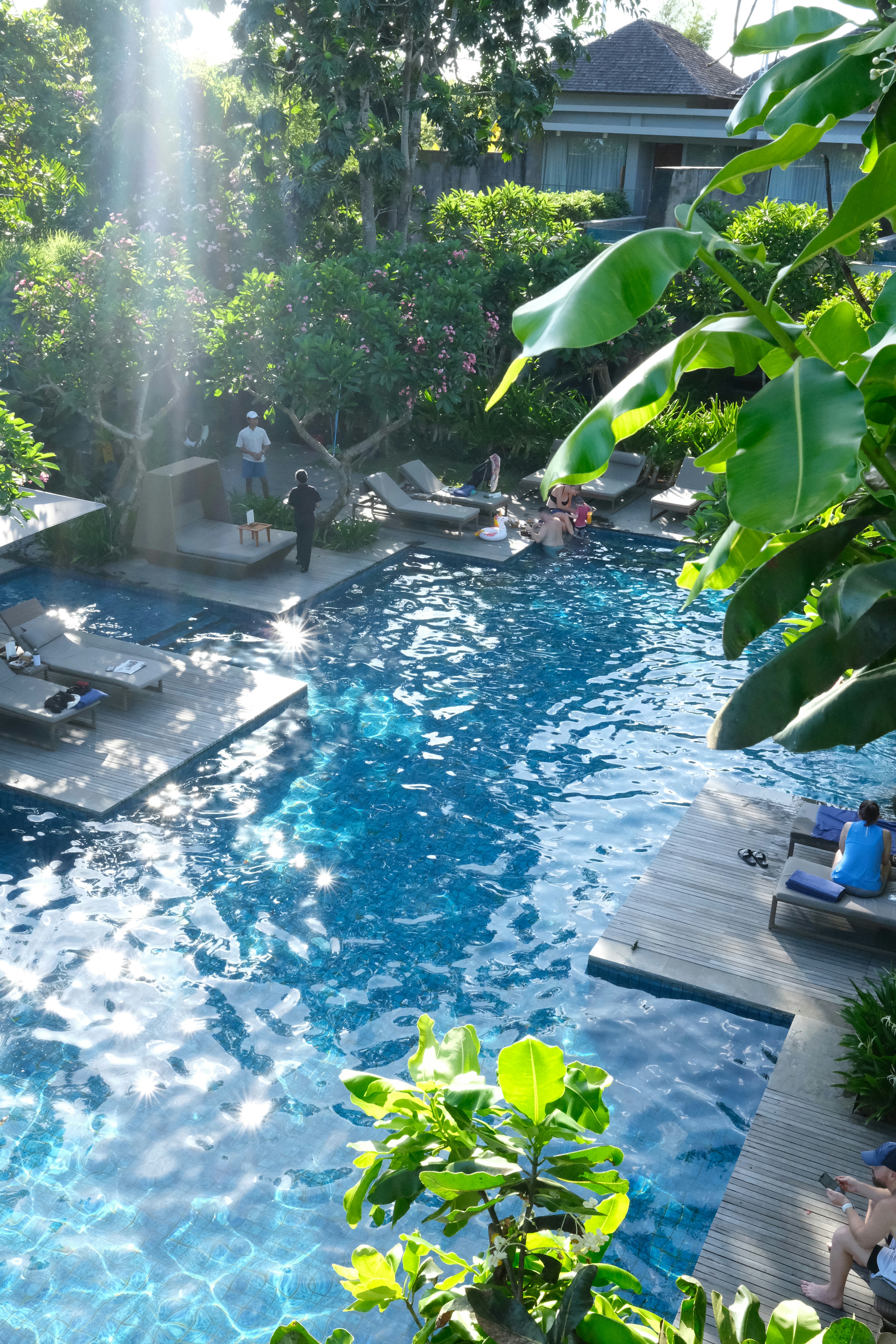 Belle piscine résidentielle avec eau claire, chaises longues et verdure luxuriante en lumière dorée