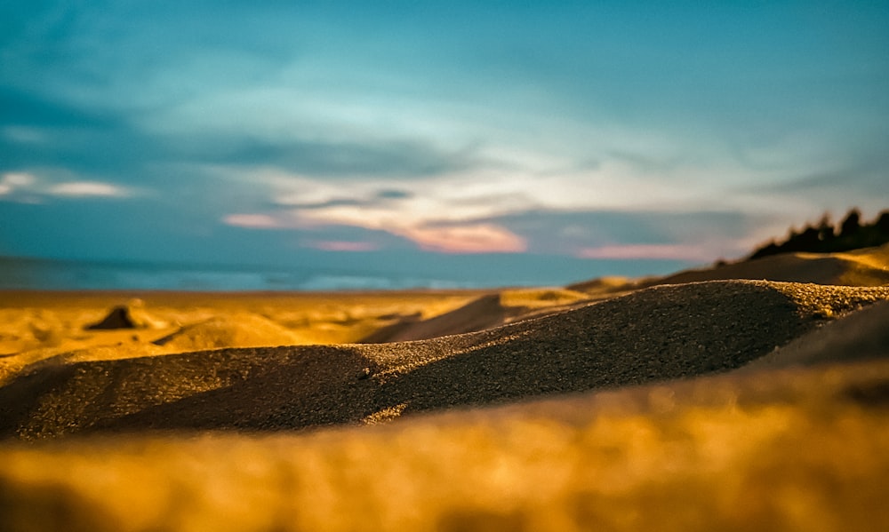 a field of sand with a sky in the background