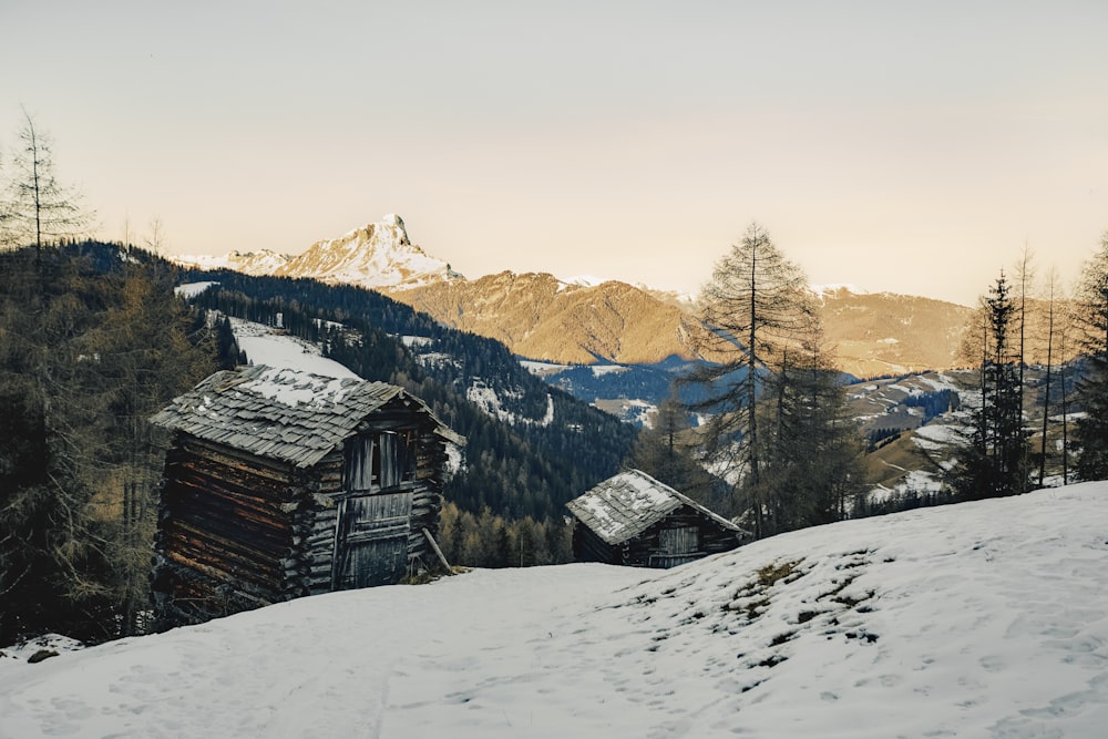 a cabin in the mountains with snow on the ground