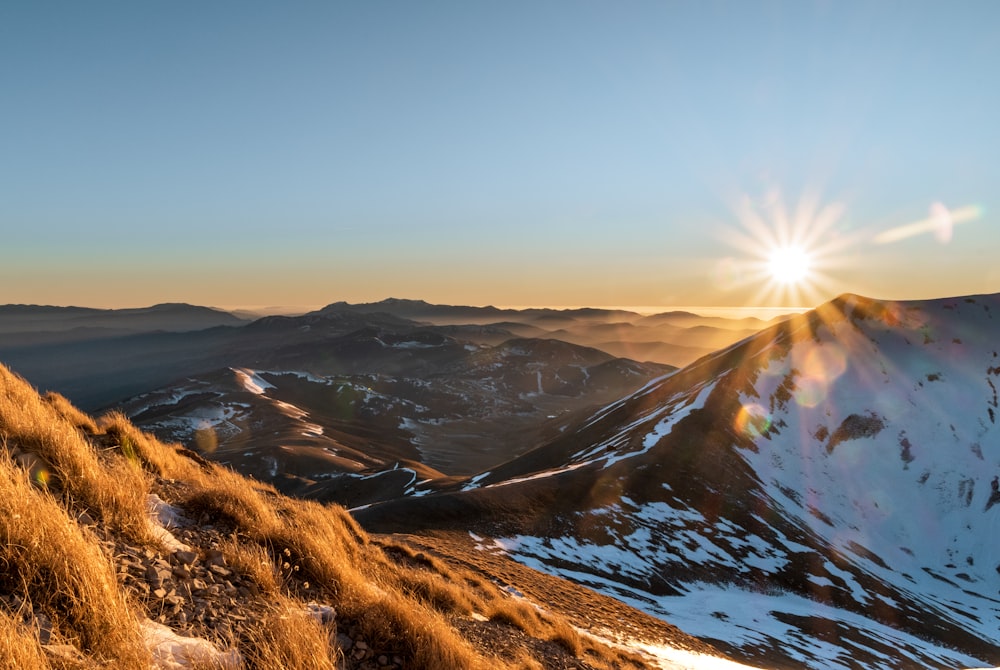 the sun is setting over a mountain range